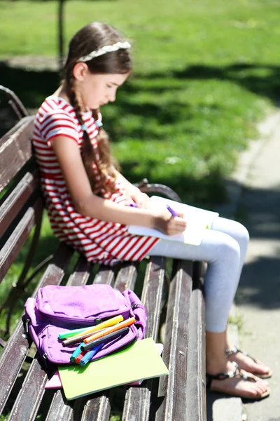 Söt flicka ritning på bänk i parken — Stockfoto