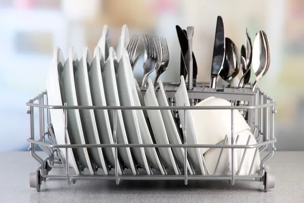 Clean dishes drying on metal dish rack on light background — Stock Photo, Image