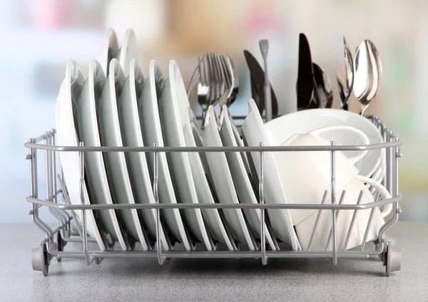 Clean dishes drying on metal dish rack on light background — Stock Photo, Image