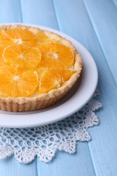 Crostata all'arancia fatta in casa su piatto, su sfondo di legno a colori — Foto Stock