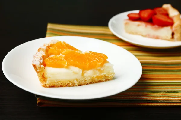 Pedaço de laranja caseira e tortas de morango na placa, na cor de fundo de madeira — Fotografia de Stock