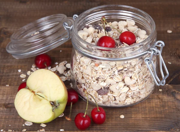 Granola fatta in casa in vaso di vetro, su sfondo di legno a colori — Foto Stock