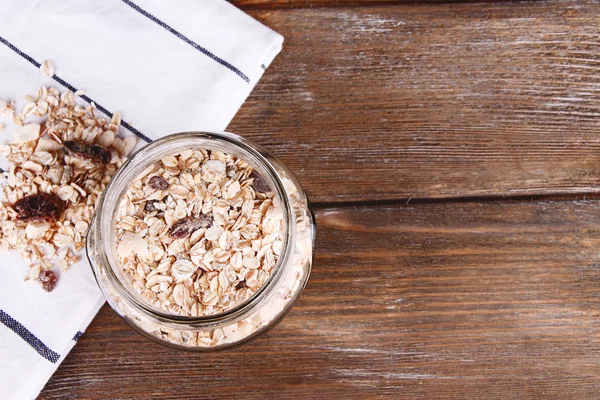 Granola fatta in casa in vaso di vetro, su sfondo di legno a colori — Foto Stock