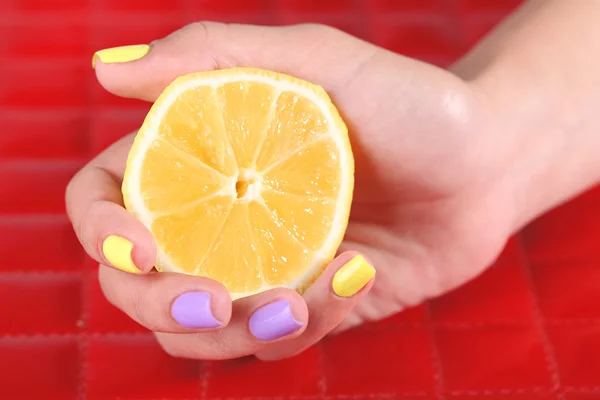 Mão feminina com unhas coloridas elegantes segurando limão fresco — Fotografia de Stock