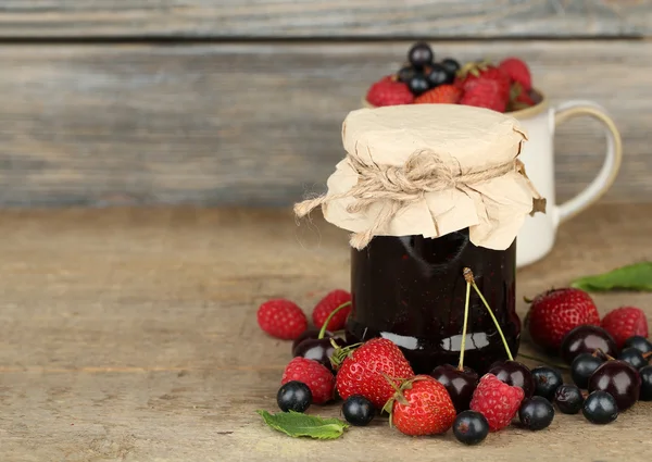 Leckere Marmelade mit Beeren im Glas auf Holztisch — Stockfoto