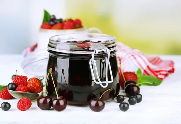 Smakelijke jam met bessen in glazen pot op houten tafel — Stockfoto