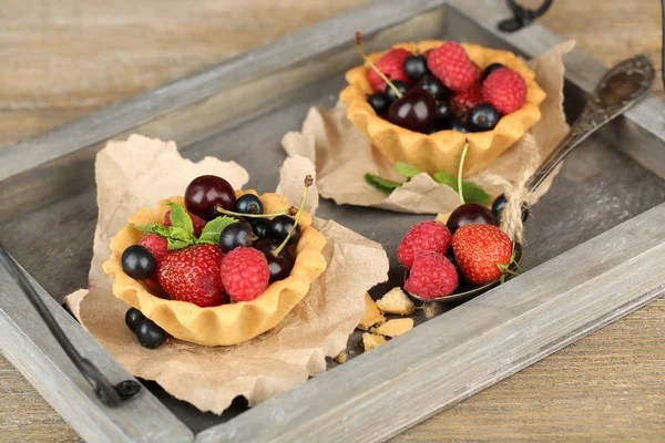 Tasty tartlets with berries on wooden tray — Stock Photo, Image