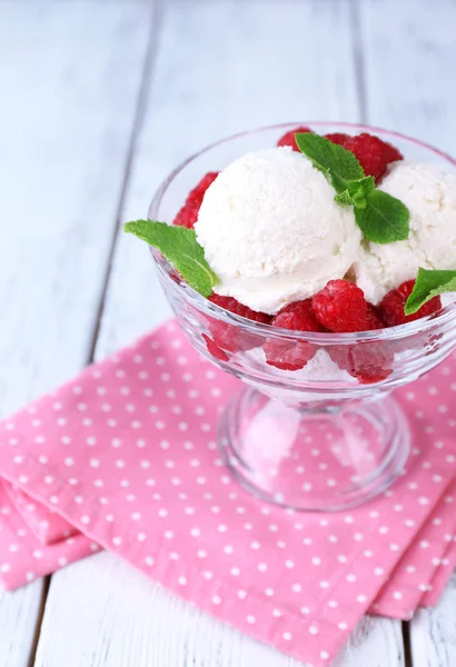 Romige ice cream met frambozen op plaat in glazen kom, op een houten achtergrond kleur — Stockfoto