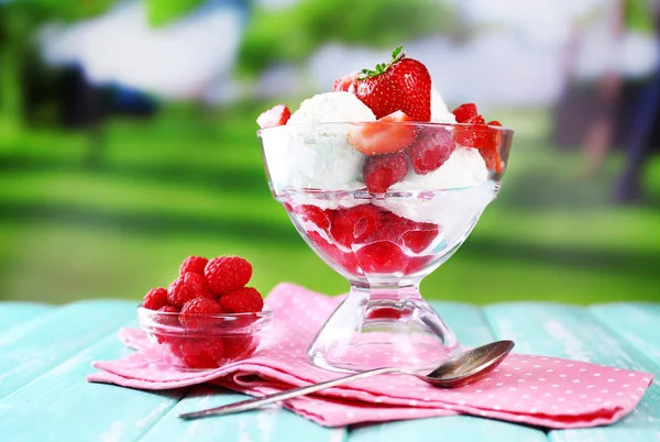 Gelato cremoso con lamponi su piatto in ciotola di vetro, su tavolo di legno a colori, su sfondo brillante — Foto Stock