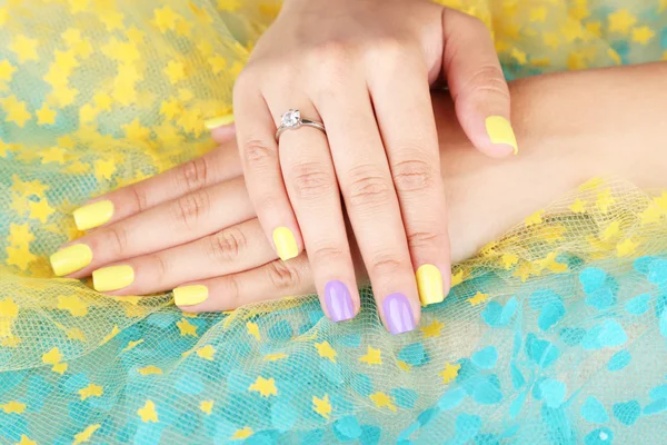 มือผู้หญิงที่มีเล็บสีสันสดใสบนพื้นหลังที่สดใส — ภาพถ่ายสต็อก