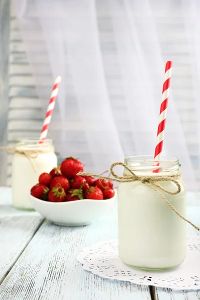 Milk in bottles with paper straws on table