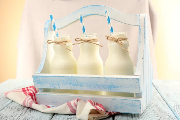 Melk in flessen met papier rietjes op tafel — Stockfoto