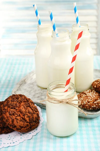 Mléko v lahvích s papírovými brčka na stole — Stock fotografie