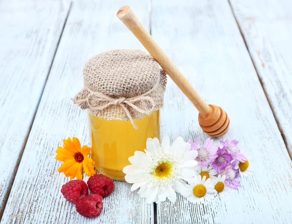 Vaso pieno di delizioso miele fresco e fiori selvatici sul tavolo di legno — Foto Stock