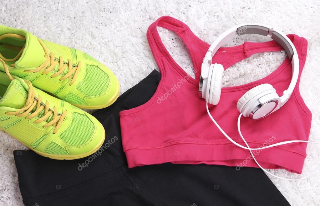 Sport clothes, shoes and headphones on white carpet background. 