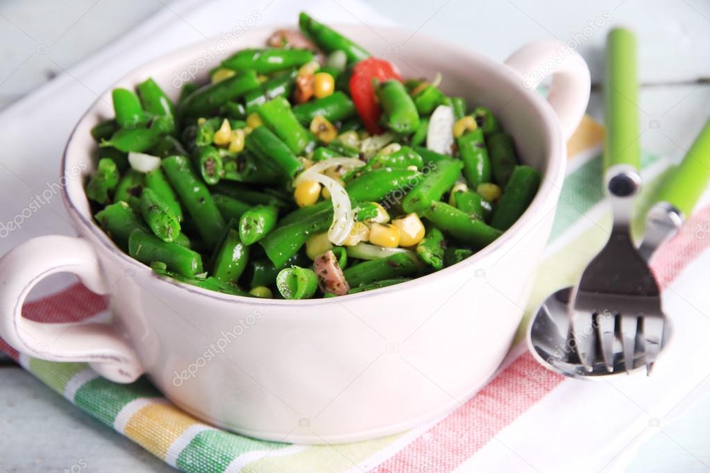 Salad with green beans, ham and  corn in bowl, on color wooden background