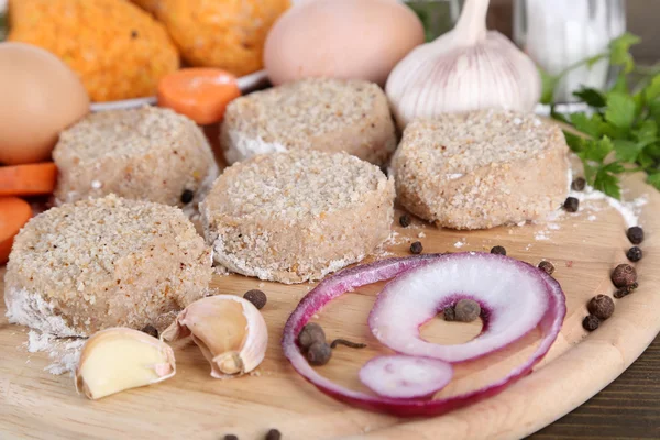 Meat patties on board and on plate on wooden table — Stock Photo, Image