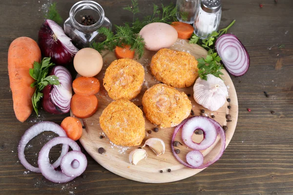 Meat patties on board on wooden table — Stock Photo, Image