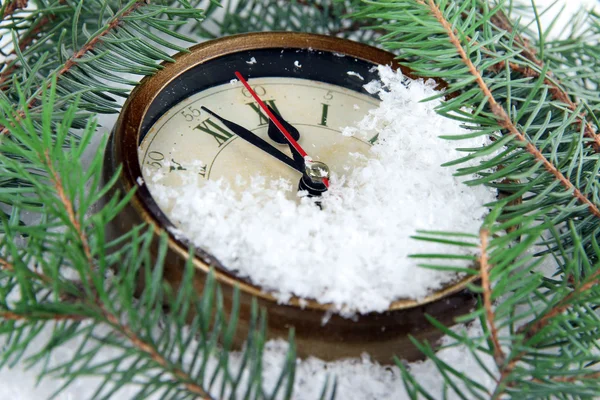 Uhr und Tannenzweige unter Schnee — Stockfoto