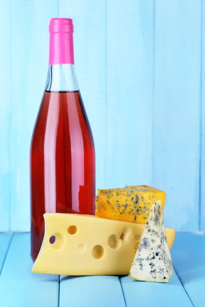 Pink wine and different kinds of cheese on wooden background — Stock Photo, Image