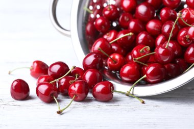 Renkli ahşap arka planda süzgeçli tatlı kirazlar