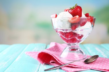 Kremalı dondurma ile Ahududu plaka cam kapta parlak arka plan üzerinde renkli ahşap masa