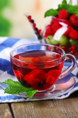 Yabani çilek cam bardakta parlak zemin üzerine ahşap masa ile kırmızı meyve çayı