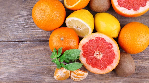 Färska citrusfrukter med gröna blad på färg trä bakgrund — Stockfoto