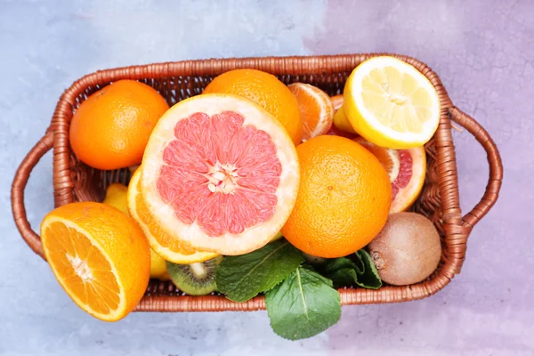 Fresh exotic fruits with green leaves in wicker basket — Stock Photo, Image