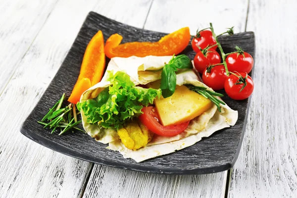 Enveloppement végétarien rempli de poulet et de légumes frais sur une table en bois — Photo