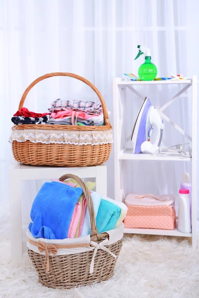 Toalhas coloridas e roupas em cestas na mesa — Fotografia de Stock