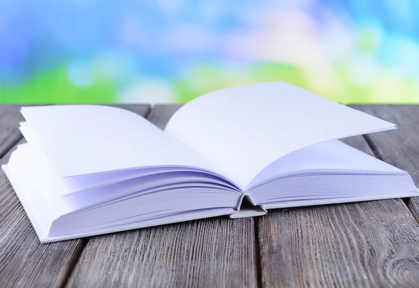 Livro branco aberto sobre mesa de madeira sobre fundo brilhante — Fotografia de Stock