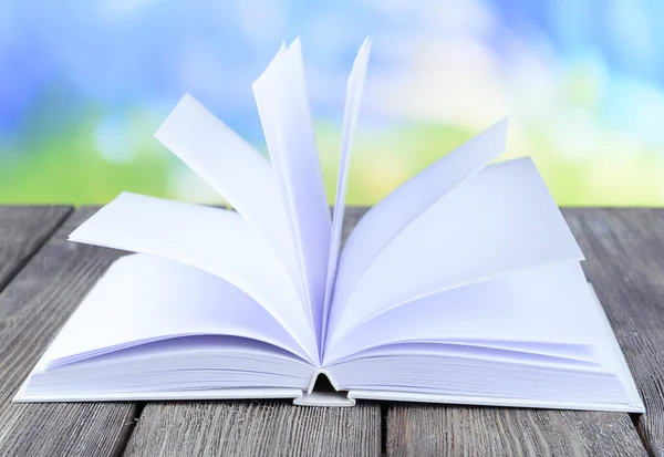 Open white book on wooden table on bright background — Stock Photo, Image