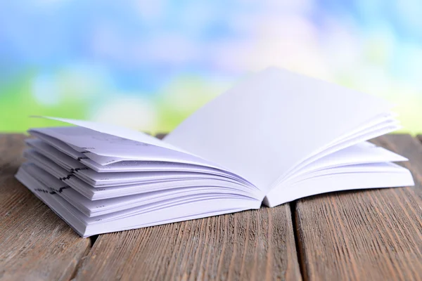 Open white book on wooden table on bright background — Stock Photo, Image