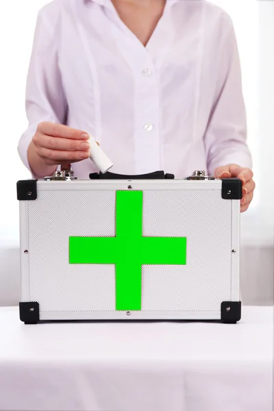 Nurse holding first aid kit in room — Stock Photo, Image