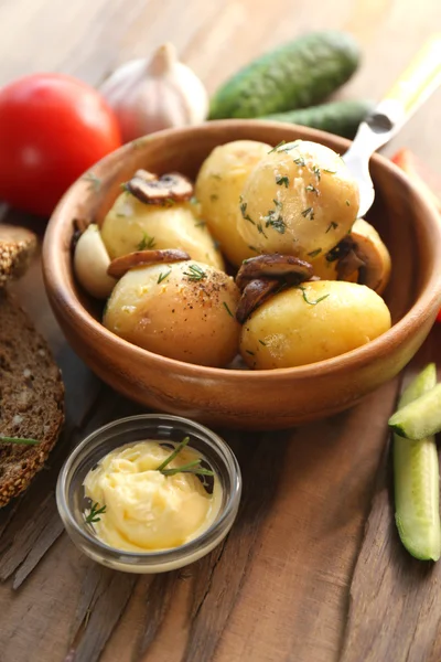 Jonge gekookte aardappelen in kom op houten tafel, close-up — Stockfoto