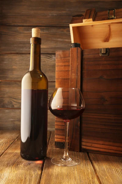 Flaskor vin med glas på trä bakgrund — Stockfoto