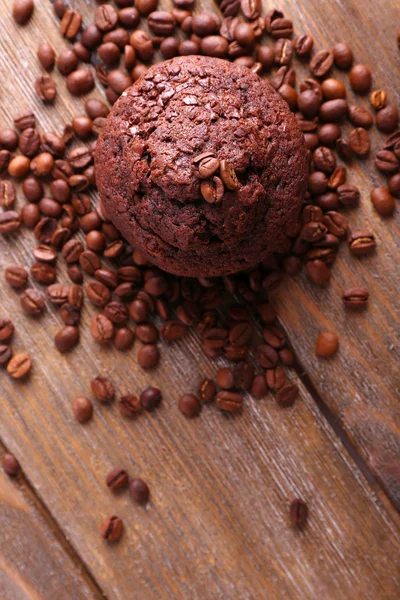 Schokoladenmuffin und Kaffeekörner auf Holzgrund — Stockfoto