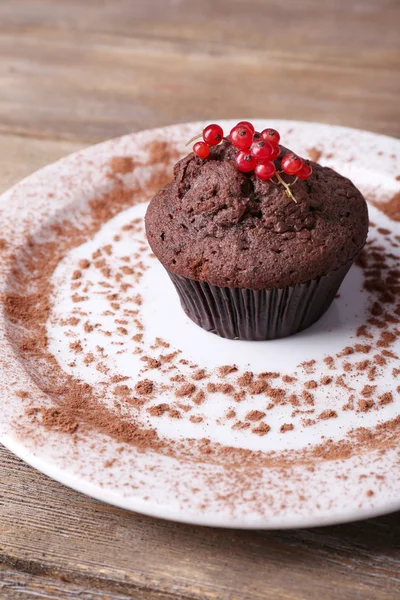 Chocolate muffin with red currant on plate on wooden background — Stock Photo, Image
