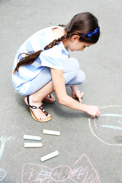 Cute girl drawing with chalk on asphalt — Stock Photo, Image