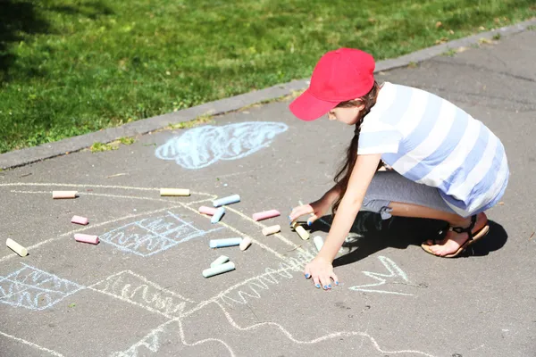 Linda chica dibujo con tiza sobre asfalto — Foto de Stock