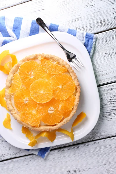 Crostata all'arancia fatta in casa su piatto, su sfondo di legno a colori — Foto Stock