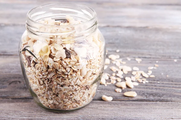 Zelfgemaakte muesli in glazen pot, op een houten achtergrond kleur — Stockfoto