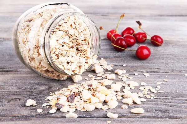 Granola fatta in casa in vaso di vetro, su sfondo di legno a colori — Foto Stock