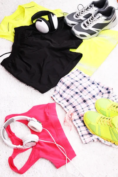 Sportovní oblečení, boty a sluchátka na pozadí bílý koberec. — Stock fotografie