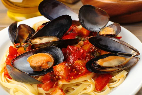 Macarrão saboroso com mexilhões na mesa — Fotografia de Stock