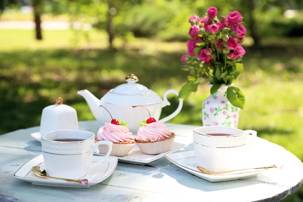 Mesa de centro con tazas de té y pasteles sabrosos — Foto de Stock