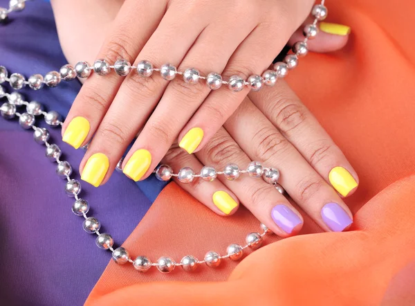 Mão feminina com unhas coloridas e pérolas elegantes — Fotografia de Stock