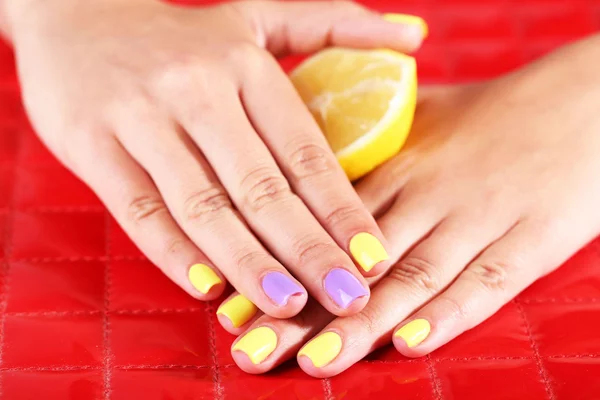 Mano femenina con elegantes uñas de colores sosteniendo limón fresco —  Fotos de Stock