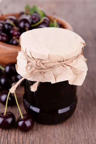 Chutné cherry jam v sklenice na dřevěný stůl — Stock fotografie